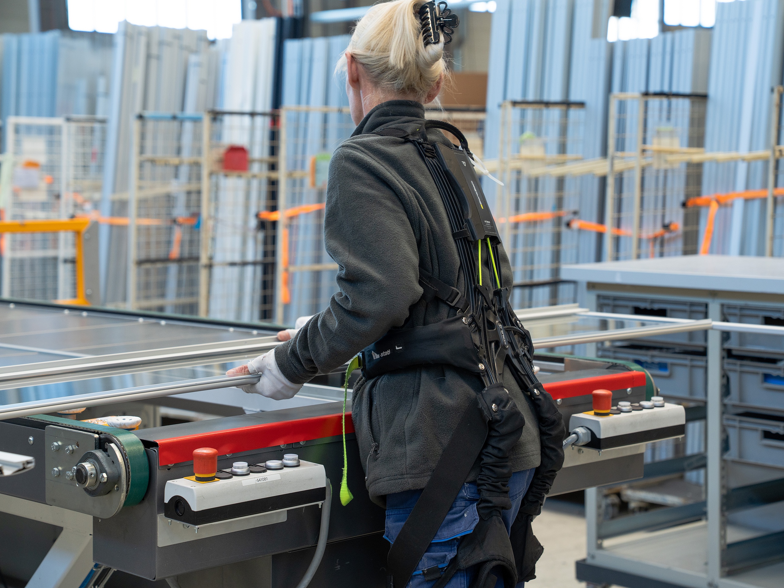 Eine Kermi Duschdesign Mitarbeiterin in der Produktion trägt eine Rückenstütze zur Entlastung Mitarbeiterin in der Produktion trägt eine Rückenstütze